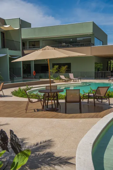 Deck da piscina com mesas e espreguiçadeiras